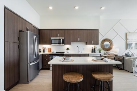 Kitchen area with island, dual sink, steel appliances, wood cabinets, and wood-style flooring