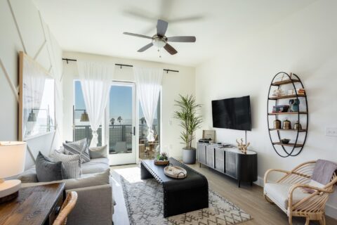 Living room with wood-style floors, couch and lounge seating, tv, windows, and balcony access