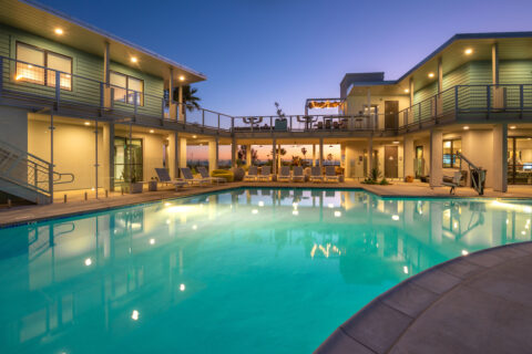 Evening shot of resort style pool with lounge style seating overlooking the ocean