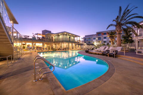 Evening shot of the resort style pool with tropical landscaping, lounge seating, and subtle lighting