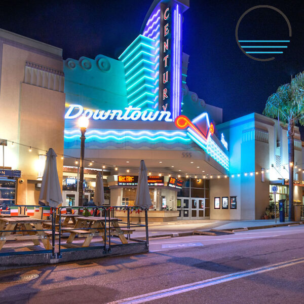 Downtown Century movie theater with patio seating outdoors, umbrella, and neon lights
