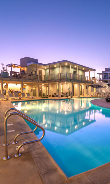 Evening shot of resort style pool with lounge style seating overlooking the ocean