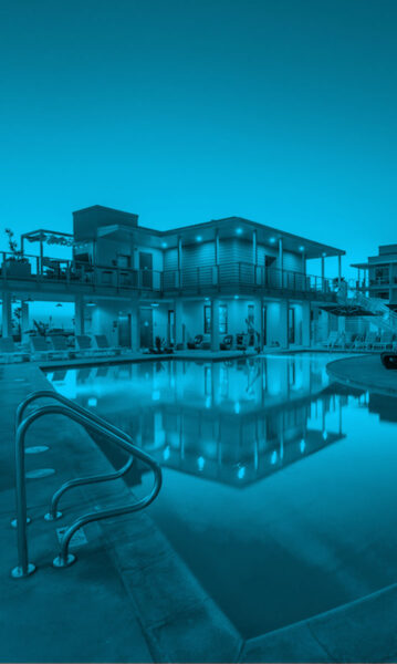 Evening shot of resort style pool with lounge style seating overlooking the ocean